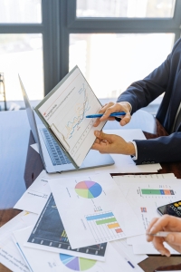 A real estate broker goes over business documents and charts with a client.
